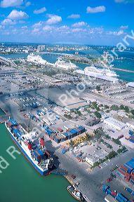 Container ship in foreground and cruise ships at the Port of Miami aerial view.