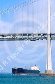 Cargo ship passing beneath San Francisco Bay Bridge.