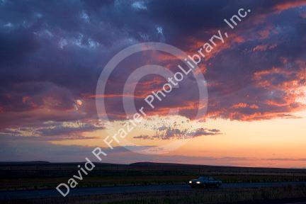 Automobile driving with headlights on at sunset in Idaho.