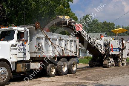 A road construction crew uses machinery to recycle asphalt in Oceola, Iowa.
