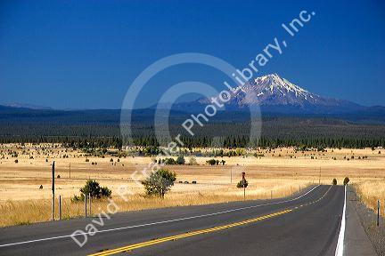 Automobiles travel on the highway near McArthur, California with a view of Mount Shasta in the background.