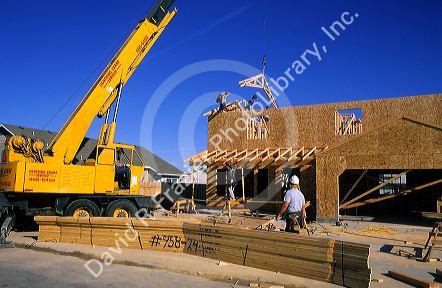 A crane lifts trusses onto the top of a new home under construction.
