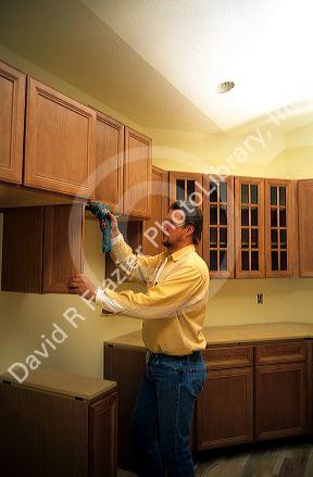 A carpenter uses a cordless power drill to install kitchen cabinets.