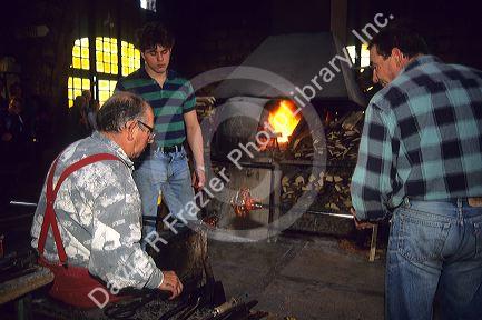 Glass blowing in Algaida, Majorca, Spain. Master, seated, apprentice at left, and journeyman at right.
