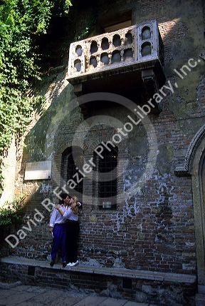 An Italian couple kissing below the balcony of Juliets house in Verona, Italy.