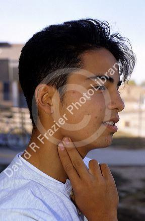 A teenage boy checking his pulse with two fingers on his neck.