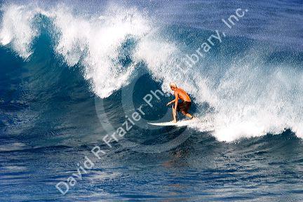 Surfing on waves in the pacific ocean off the island of Maui, Hawaii.