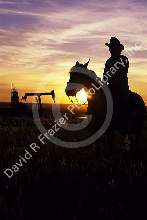 A silhouetted cowboy and oil well at sunset in North Dakota.