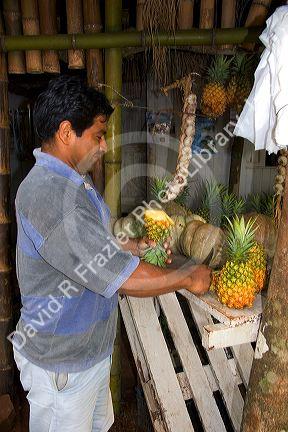 Man cuts pineapple at a produce stand in Argentina.