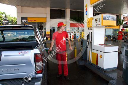 Worker pumping gas at a gas station in Argentina.