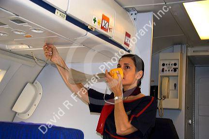 Flight attendant showing how to use an oxygen mask in case of emergency.