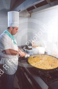 Spanish chef making paella,  rice and fish dish.