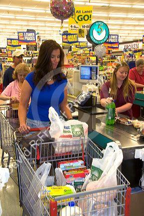 Woman leaving checking out with shopping cart full of grocery bags at Ray's Market Place in Lima, Ohio.