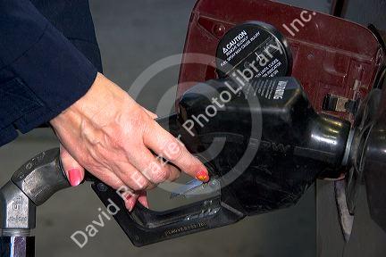 A woman's hands pumping gasoline into a car.