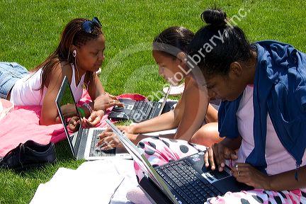 African american female students study using laptop computers on the lawn of Albion College in Michigan.