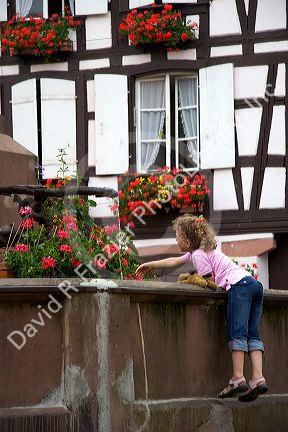 Young girl playing in a water fountain at the village of Ribeauville, Eastern France.