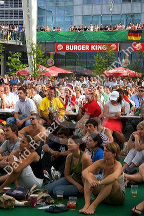 A crowd of soccer fans gather outdoors at the Munich airport watch a 2006 World Cup match on big screen televisions, Germany.