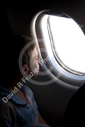 A young boy looking out the window of an airplane.
