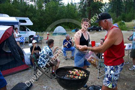 Campers preparing shish kabob meal.