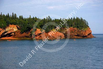 People sea kayaking in the Bay of Fundy at St. Martins, New Brunswick, Canada.