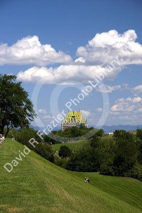 People walk up a grassy hill with the Chateau Frontenac in the background at Quebec City, Quebec, Canada.