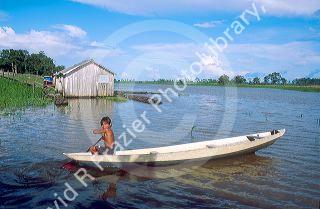 Native boy paddling his canoe on an arm of the Amazon River near Manaus Brazil.