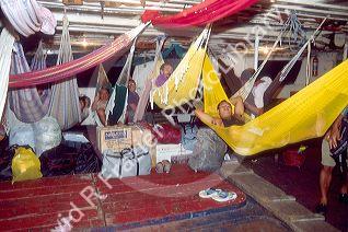 Brazillian people on a riverboat resting in hammocks.