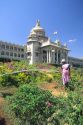 Worker watering flowers at Vidhana Soudha, state capitol in Bangalore, India.