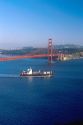 Container ship loaded with cargo passes beneath the Golden Gate Bridge at San Francisco headed out to sea.