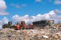 Sanitary landfill with gulls flying overhead and compactors at work.