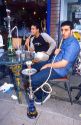 Turkish men smoking tobacco with a water pipe at a sidewalk cafe in London, England.