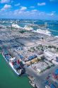 Container ship in foreground and cruise ships at the Port of Miami aerial view.