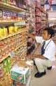 A hispanic employee stocks the shelves in a supermarket.