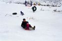 Grandfather sledding with his grandaughter in the snow.