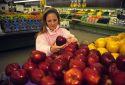 A young woman shopping for fruits and vegetables in a supermarket.