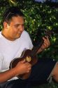 A hawaiian teen plays the ukalele.