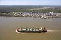 Bulk material cargo ship passing petro chemical refinery near New Orleans, Louisiana.