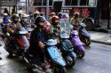 People wearing helmets ride motorscooters in Taipei, Taiwan.