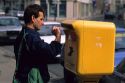 French man deposits a letter into a mailbox in France.