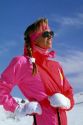 A woman snow skiing with sun glasses and nylon waterproof clothing.