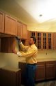 A carpenter uses a cordless power drill to install kitchen cabinets.
