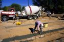 Worker smoothing freshly poured concrete footings, Idaho.