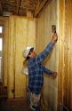 Construction worker installing a plastic vapor barrier over insulation in a new home.
