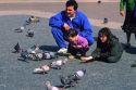 Father and children feed pigeons in Barcelona, Spain.