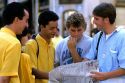 Tourist information guides (in yellow shirts) look at a map and offer directions in Madrid, Spain.