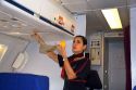 Flight attendant showing how to use an oxygen mask in case of emergency.