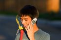 Teen lacrosse player using a cell phone.