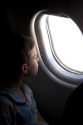 A young boy looking out the window of an airplane.