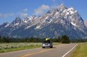 Vehicle traveling with canoe on roof on the highway through Grand Teton National Park, Wyoming.