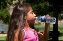 Young hispanic girl drinking water out of a bottle.